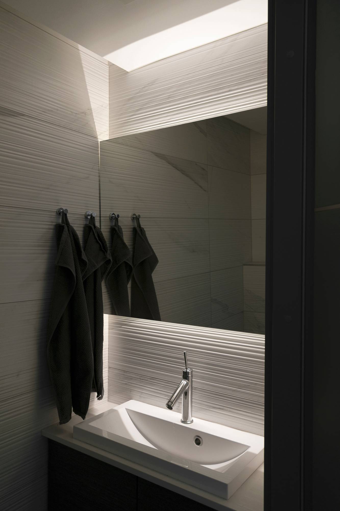 Detrás del espejo, unas tiras de leds iluminan el cuarto de baño con luz indirecta. Las tiras de luz también acentúan la textura de los azulejos. Ledstore.fi