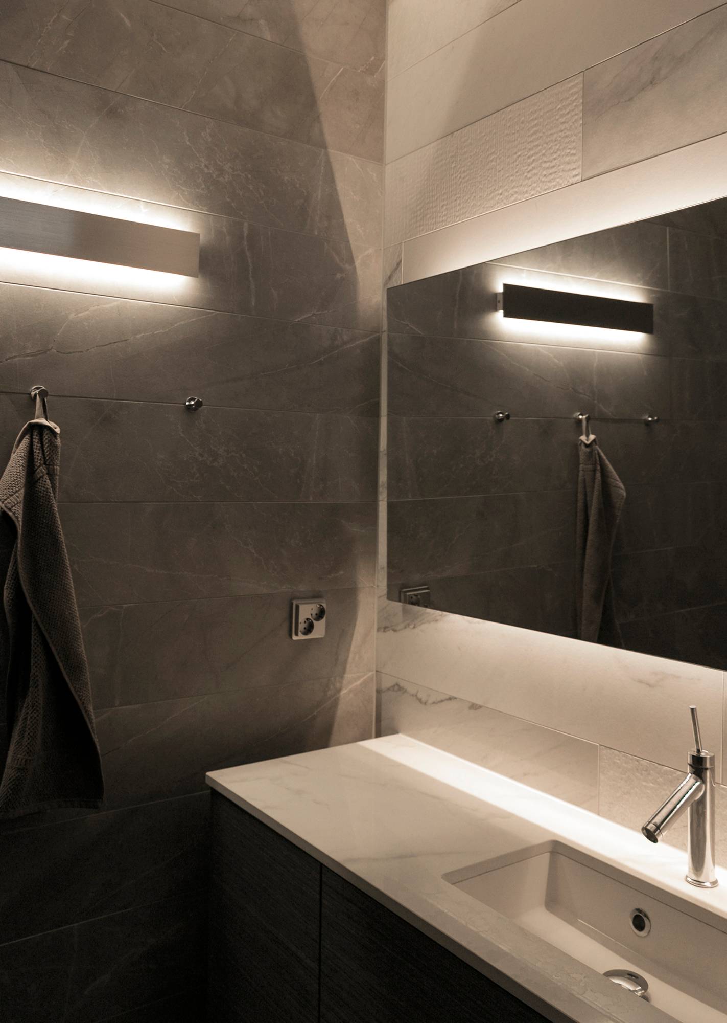 En el cuarto de baño, luz indirecta en dos direcciones procedente de un aplique RECTO y tiras de LED detrás del espejo. Ledstore.fi