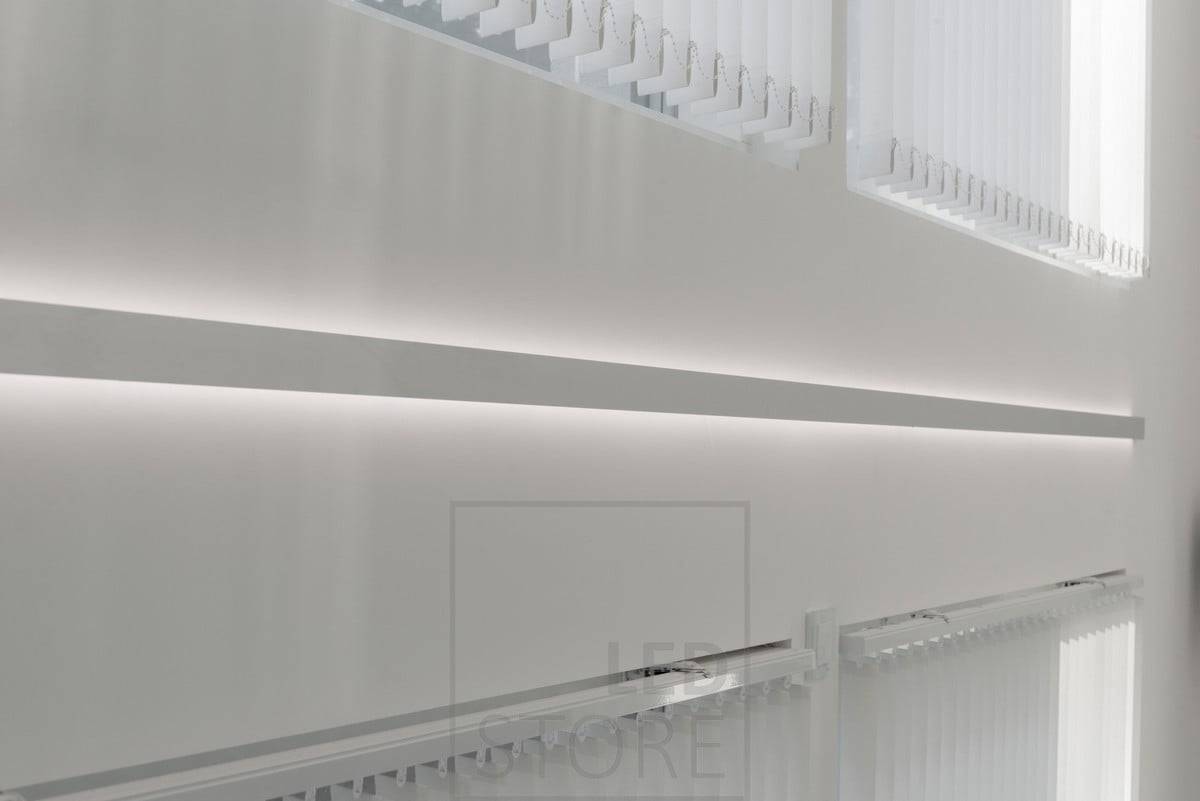 Un perfil de pared bidireccional para tiras de luces LED, instalado entre ventanas. La luz es atmosférica e indirecta. Ledstore.fi