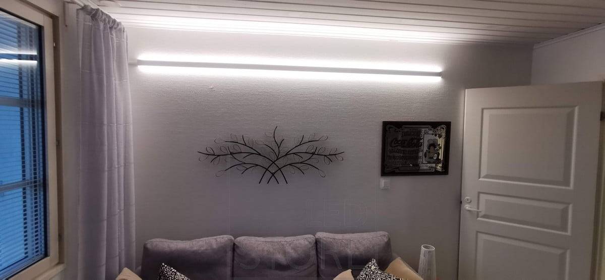 Detrás del sofá, en la pared, un perfil LED bidireccional. El perfil tiene dos tiras de LED. Ledstore.fi