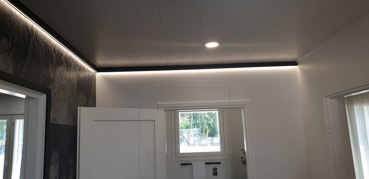 Un decorativo perfil de pared negro con una tira de luz led que proporciona luz indirecta. Ledstore.fi