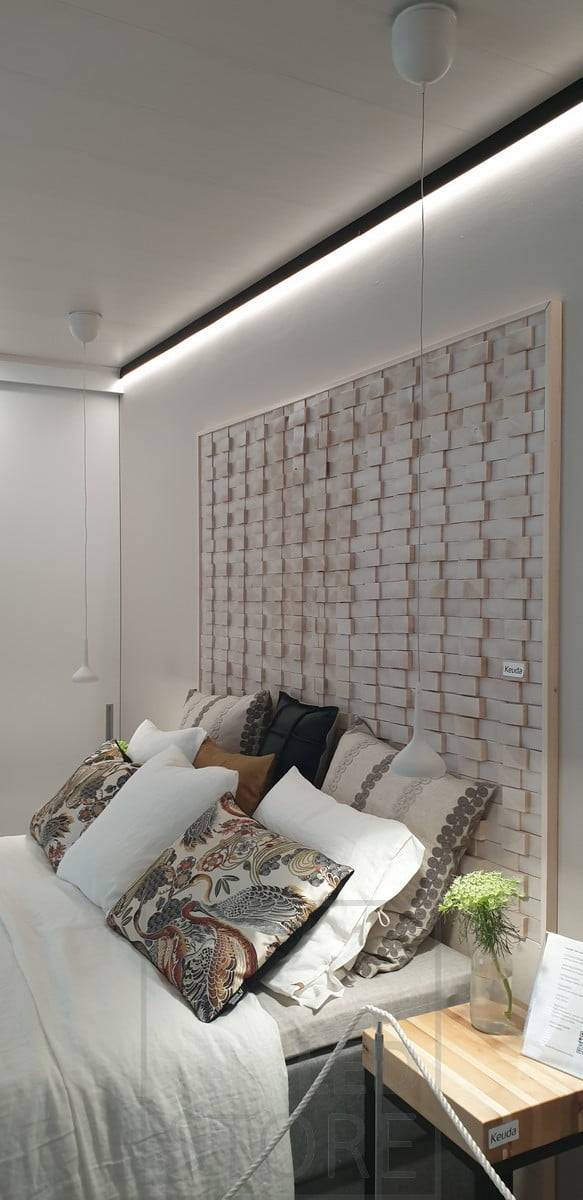 Detrás de la cama, un perfil de pared negro en el techo para sustituir la moldura del techo. Tira de luz led que ilumina hacia abajo con luz indirecta a través de la pared. Ledstore.fi