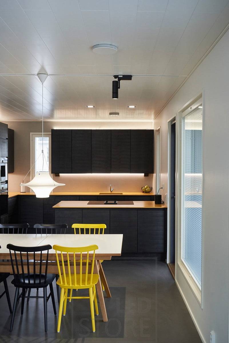 En la cocina, tiras de leds en la parte superior e inferior de los armarios superiores, que proporcionan una iluminación ambiental indirecta y una iluminación de trabajo a nivel de la cocina. En el comedor, focos FOKUS de Ledstore en un carril trifásico. Ledstore.fi