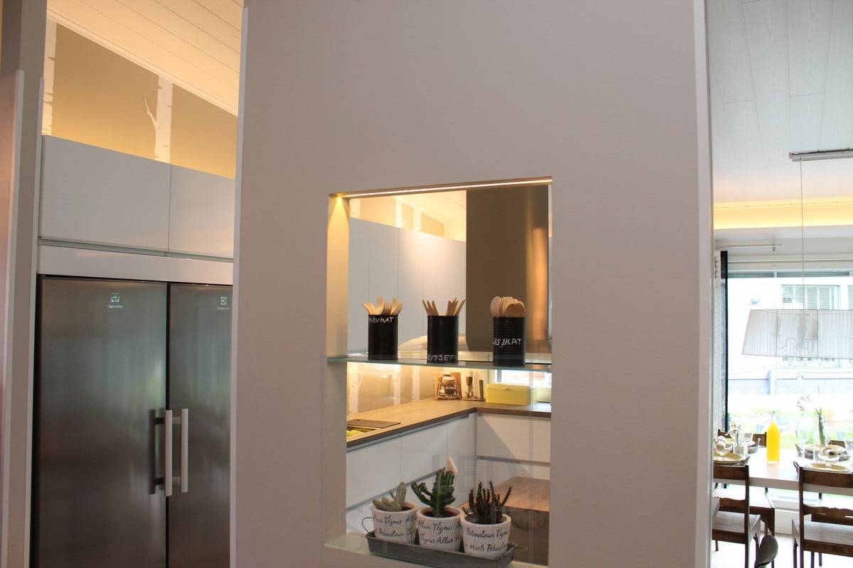 Iluminación de cocina con tiras de leds encima de los armarios y sobre la encimera, además de resaltar la bonita estantería de la pared divisoria. Ledstore.fi