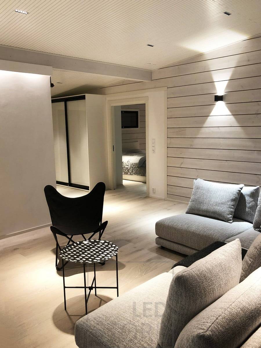 Iluminación atmosférica y versátil en el salón. Una tira de LED detrás del techo ilumina el espacio de forma indirecta, focos LINJA en el techo y un aplique FUNK en la pared. Ledstore.fi