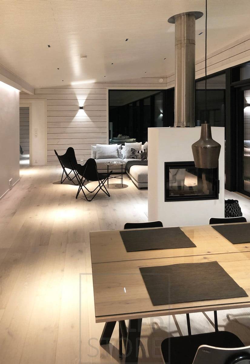 Focos LINJA como iluminación de techo en el salón y el comedor. Además de la iluminación general de ángulo estrecho, el espacio está iluminado por apliques FUNK, una tira de LED entre el techo y la pared y luces decorativas desde el techo. Ledstore.fi