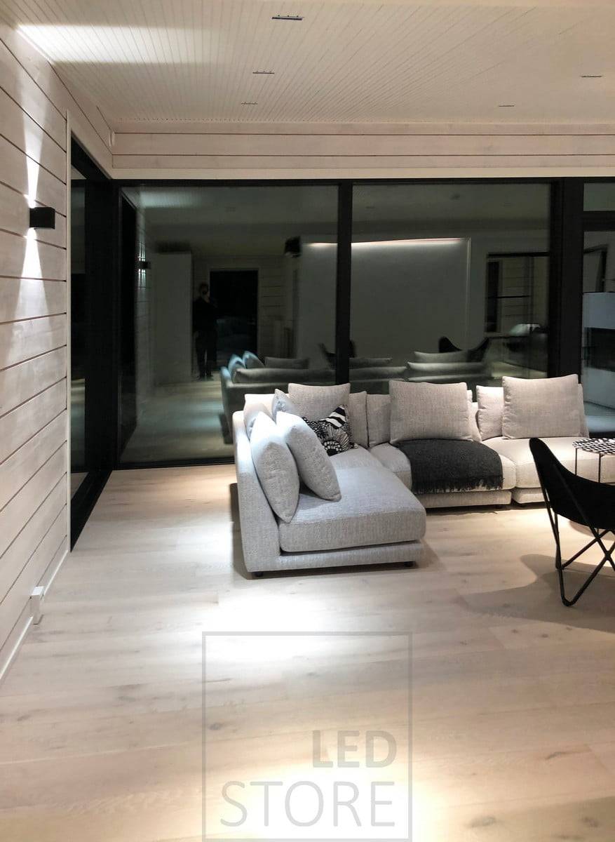 Focos LINJA como iluminación de techo en el salón y un aplique FUNK que ilumina la pared en dos direcciones para crear una luz de ambiente. Ledstore.fi