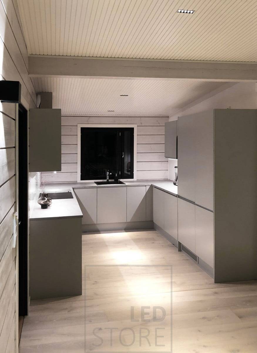 Focos LINJA 5 en el techo de la cocina. Encimeras iluminadas por tiras de LED fijadas a la parte inferior de los armarios superiores. Ledstore.fi