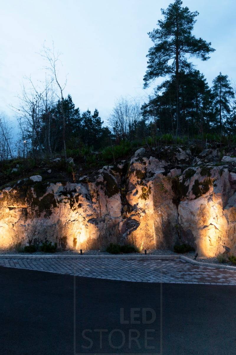 Luces de suelo SPIKE que iluminan una roca con luz atmosférica e indirecta. Ledstore.fi