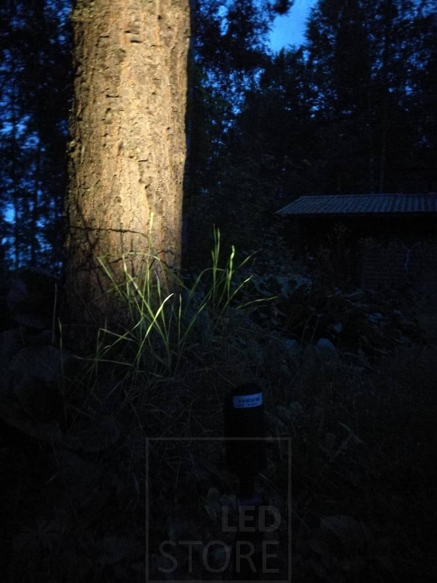 Pico de luz Led para suelo que ilumina un árbol. La lámpara tiene potencia suficiente para iluminar incluso objetos grandes en exteriores. Ledstore.fi