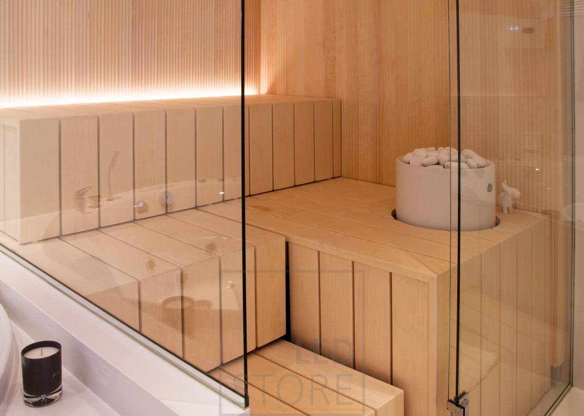 Iluminación de sauna con tira led en la ranura detrás del banco, luz dirigida hacia arriba. Ledstore.fi