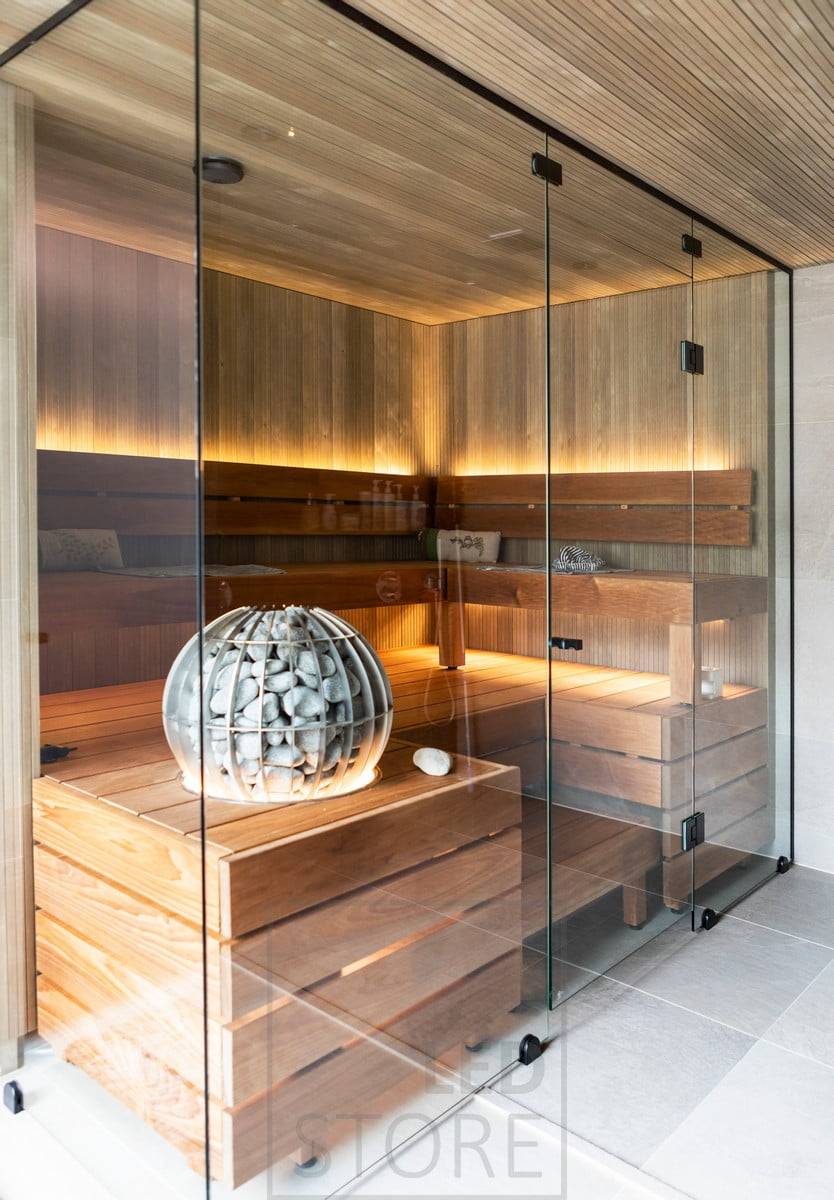 Iluminación ambiental para la sauna creada mediante luz indirecta, con la tira de LED del respaldo hacia arriba y debajo del banco hacia abajo. Ledstore.fi