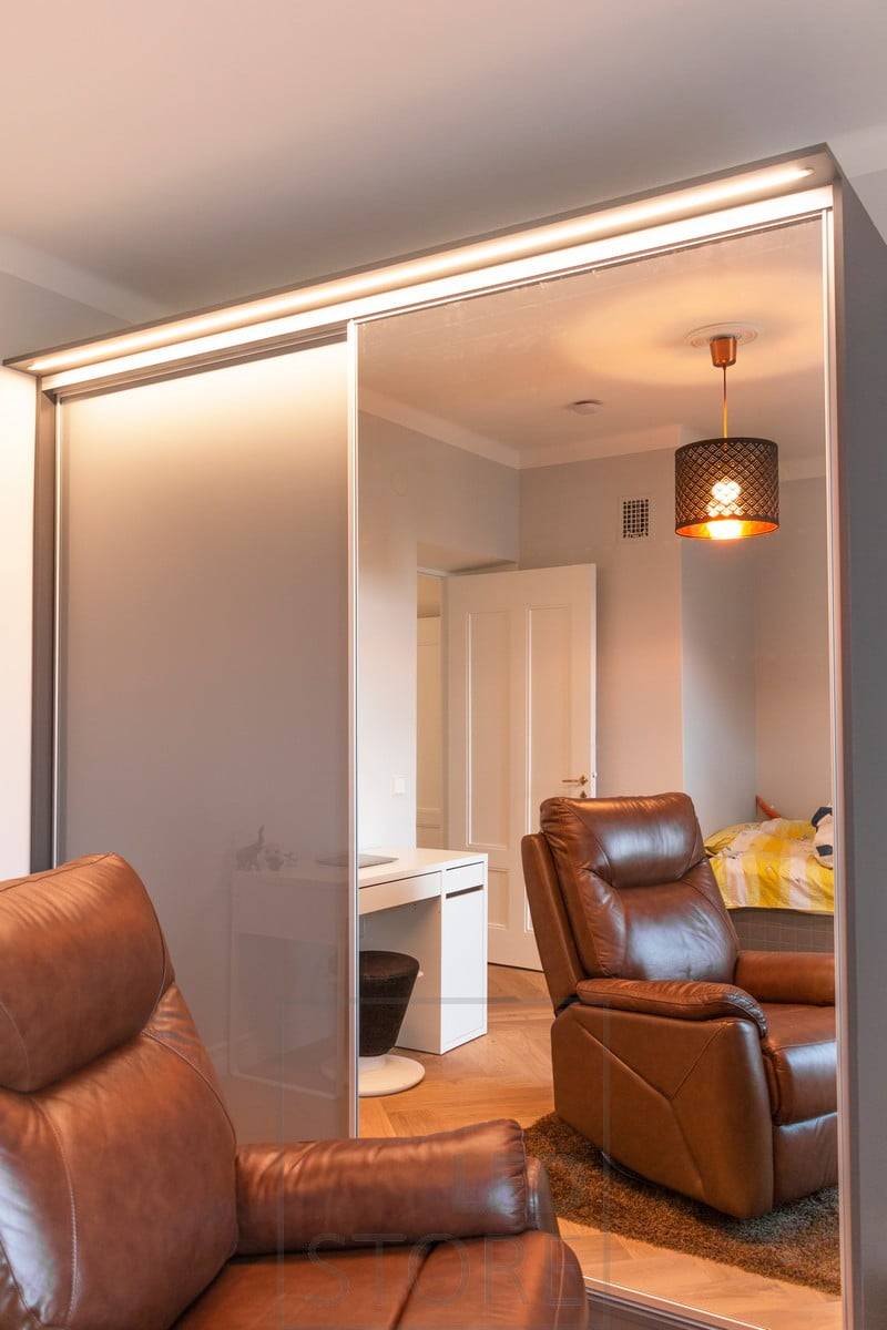 Tira de luz led en perfil estrecho empotrado que ilumina un armario sobre un cajón empotrado. La luz ilumina el espacio a su alrededor y el espejo, así como el interior del armario. Ledstore.fi