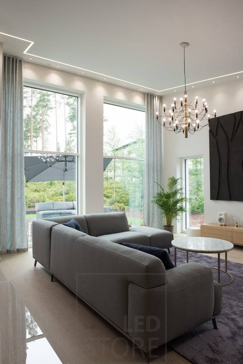 En un estrecho perfil enrasado, una tira de LED envuelve la sala de estar. La tira de LED combinada con pequeños puntos uniformemente espaciados crea un efecto de iluminación atmosférico y eficaz que también es compatible con la iluminación interior. Ledstore.fi