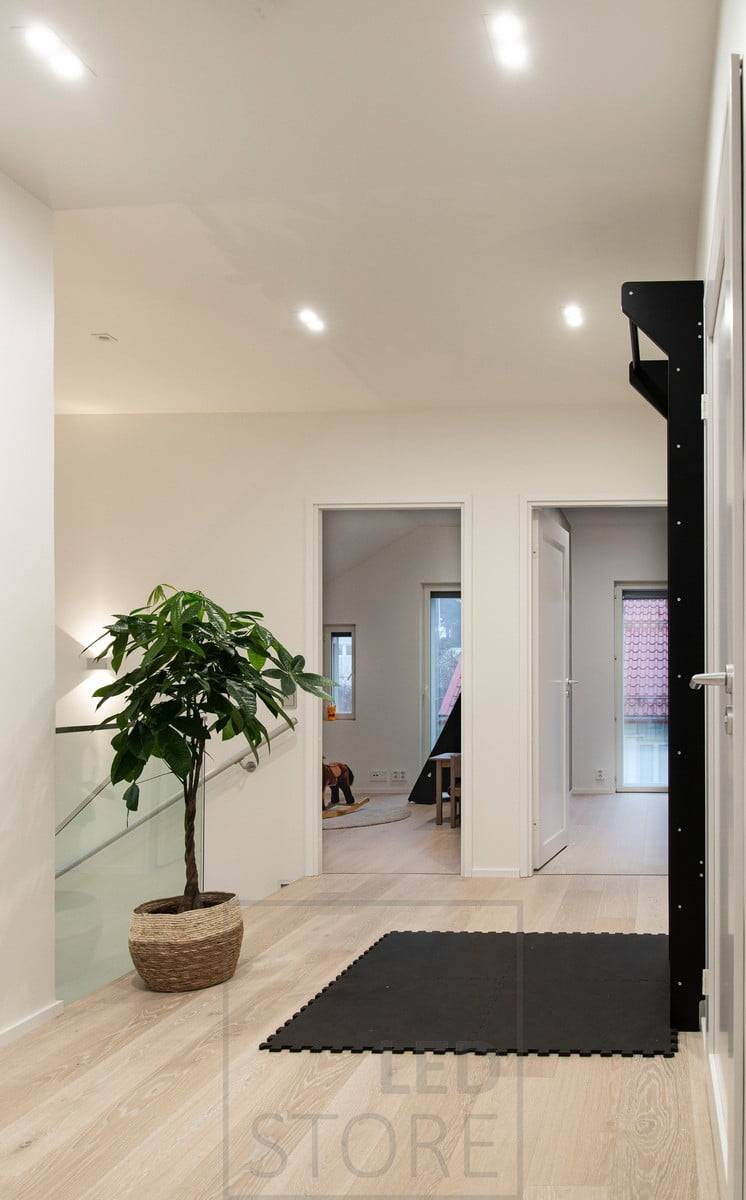 Iluminación general con focos led TUPLAKANTTI en el techo y un aplique bidireccional en la pared para crear una luz cambiante en la escalera. Ledstore.fi