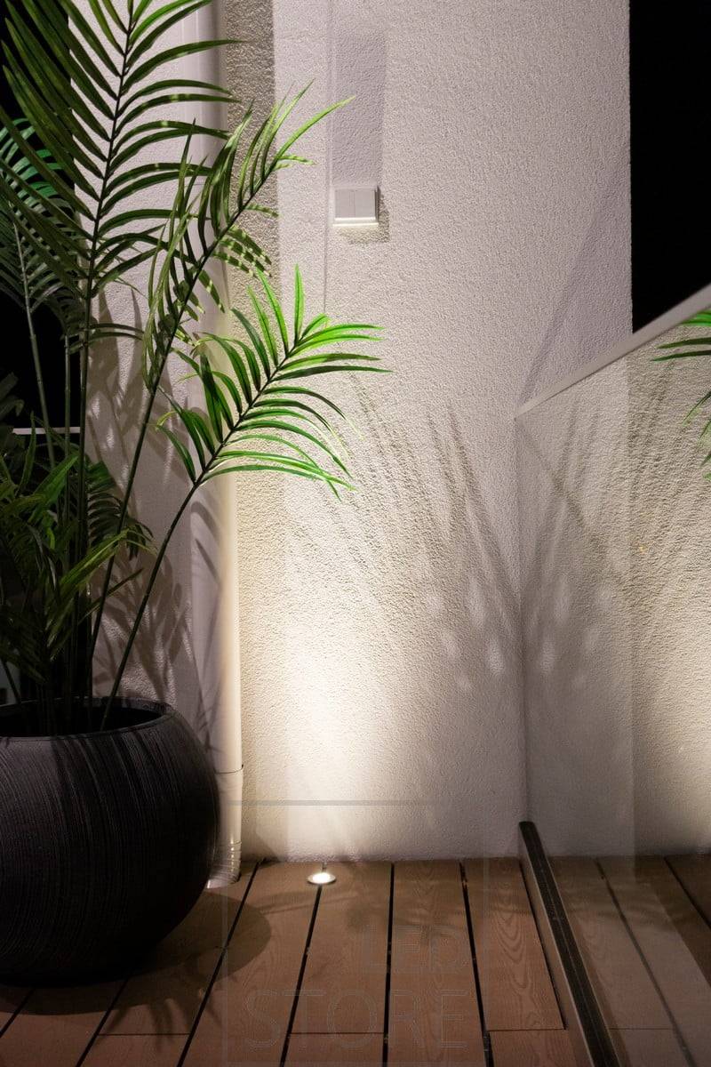 Un foco de iluminación ascendente empotrado en la terraza utiliza la pared como superficie reflectante para iluminar la estancia con luz atmosférica de abajo arriba. Ledstore.fi