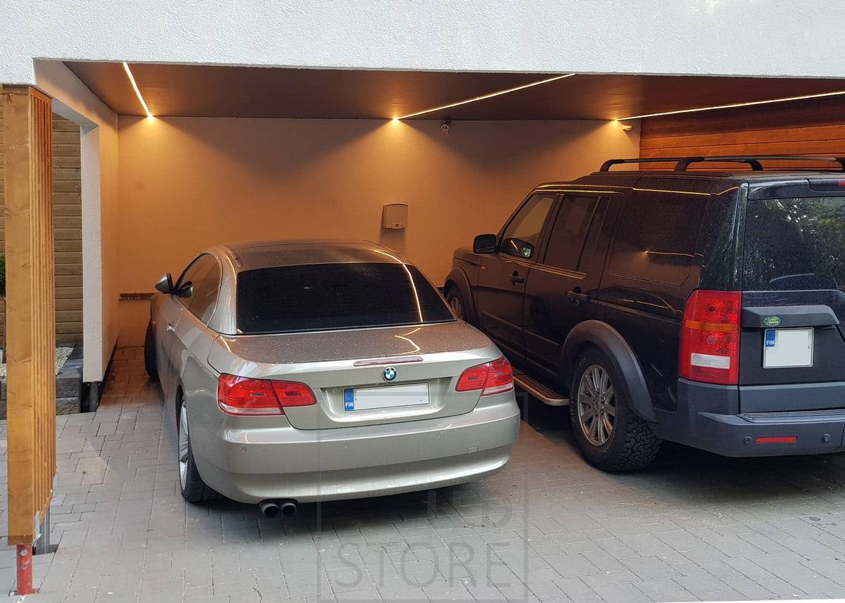 Tira de LED en el techo de una cochera en una superficie de perfil bajo. Colocada de forma que la luz no se detenga en el techo del coche, sino que ilumine los laterales del coche para que la luz esté donde se necesita. Ledstore.fi