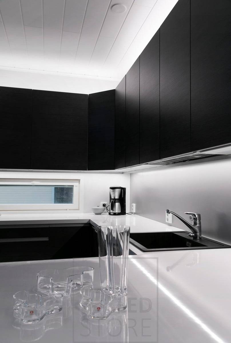 En la cocina, tiras de luces LED sobre los armarios y la encimera. Ledstore.fi