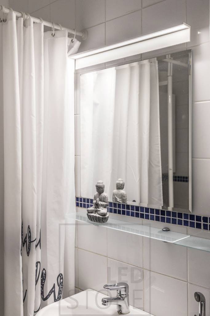 Aplique de pared Blade en el baño, iluminando el espejo y la cara. Ledstore.fi