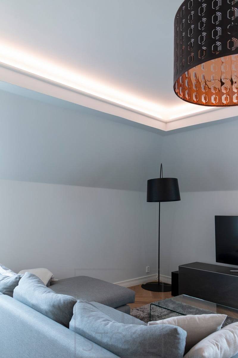 En el techo de una puerta corredera de cristal rebajada, una tira de LED ilumina indirectamente el salón. Ledstore.fi