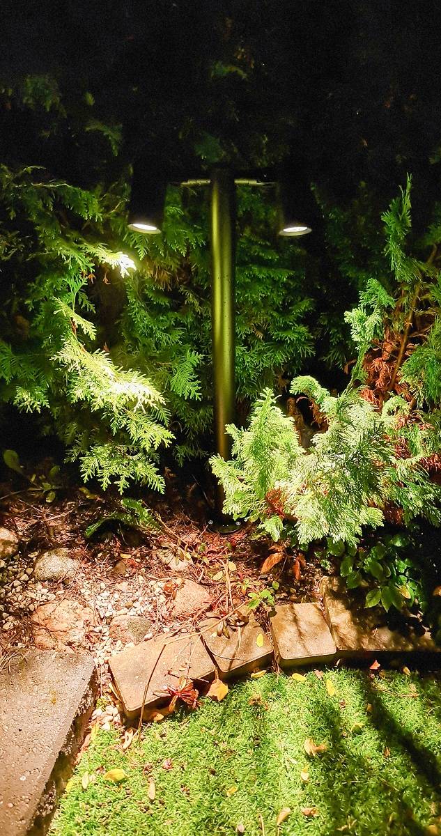 Pilar TILT 2 instalado en un jardín exterior. Ilumina las plantas del parterre al anochecer.