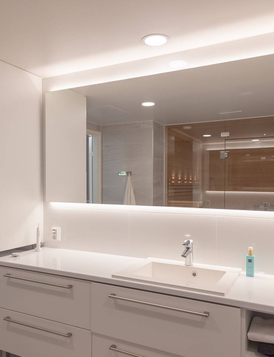 Encima del lavabo, una lámpara de techo proporciona un foco de luz y un espejo retroiluminado añade luz indirecta al espacio. ©LedStore