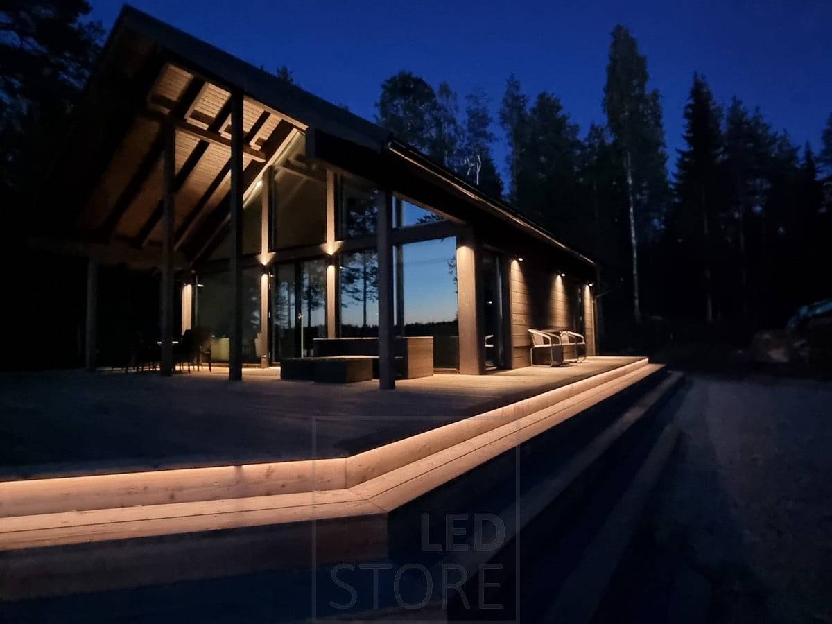 Iluminación exterior versátil y atmosférica con tira de LED en la escalera y apliques de pared. Apliques que iluminan en dos direcciones en un punto alto y en una dirección en un punto bajo. Ledstore.fi