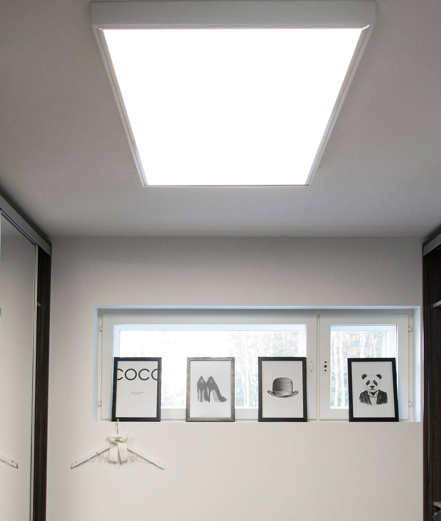 panel de 600x1200 en el techo de un pasillo en un marco de superficie. La gran luminaria se asemeja a una claraboya e ilumina el espacio de forma uniforme y eficiente. Ledstore.fi