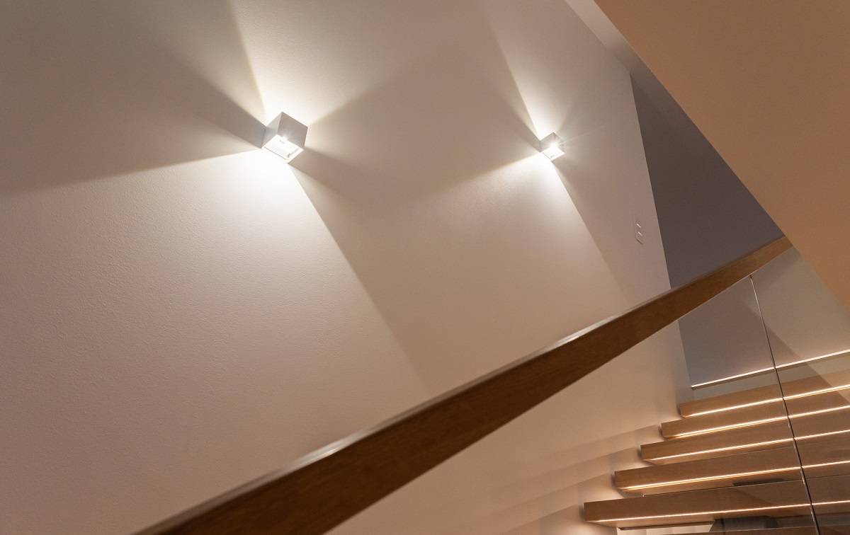 Una escalera moderna con peldaños de madera y barandilla de cristal adquiere un aspecto estupendo con los elegantes apliques LED de LedStore.fi, que crean bonitos patrones de luz en la pared. ¡Elige una iluminación de diseño que dé a tu casa un aspecto moderno!