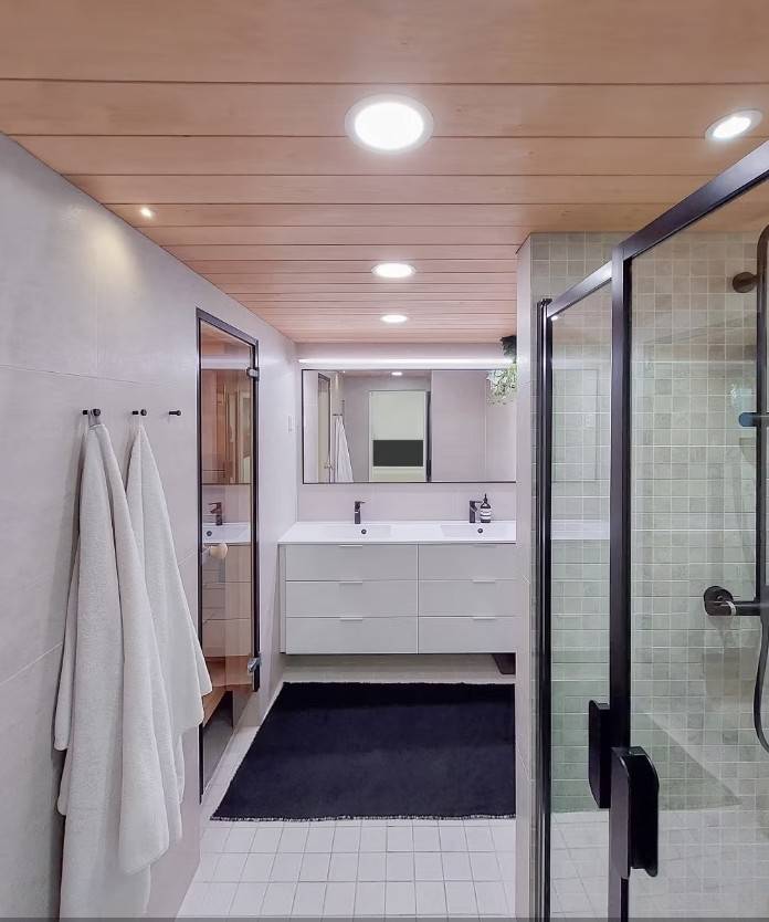 Iluminación del baño con paneles luminosos, focos, rieles de luz LED delante del espejo y focos estancos en la parte superior del lavabo.