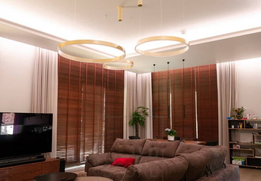 La iluminación indirecta de tiras de LED en el salón se instala tanto a lo largo del techo como delante de las cortinas para iluminar hacia abajo. Acompañada de una elegante iluminación interior.
