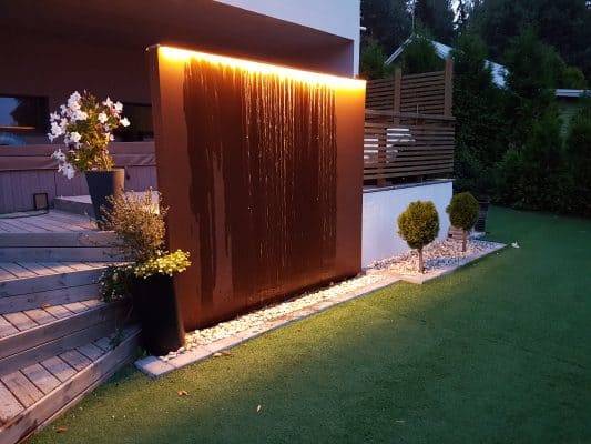 Una moderna fuente de agua para el jardín, con una tira de LED en la parte superior que se ilumina hacia abajo.