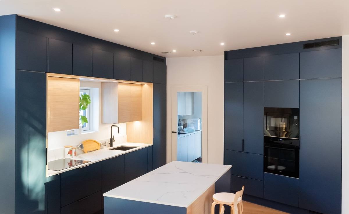 Los focos LED, espaciados uniformemente delante de los armarios, proporcionan una buena iluminación general en una cocina abierta.