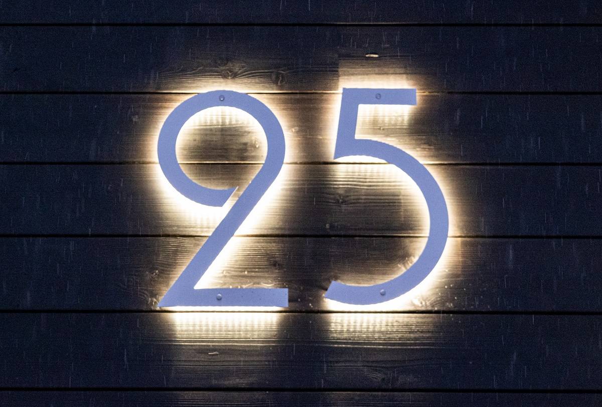 Número de casa iluminado con leds contra una pared oscura