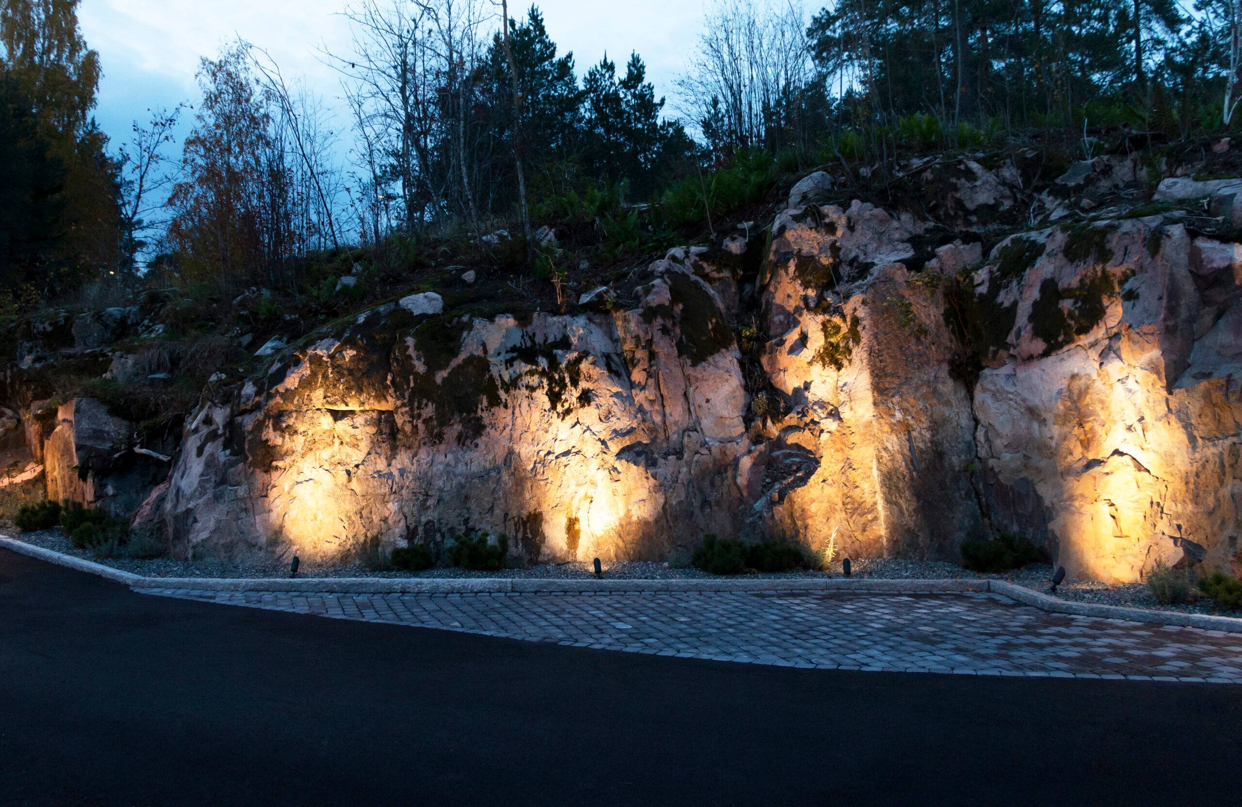 En el borde del patio rocoso, las luces paisajistas LED acentúan las formas rígidas.