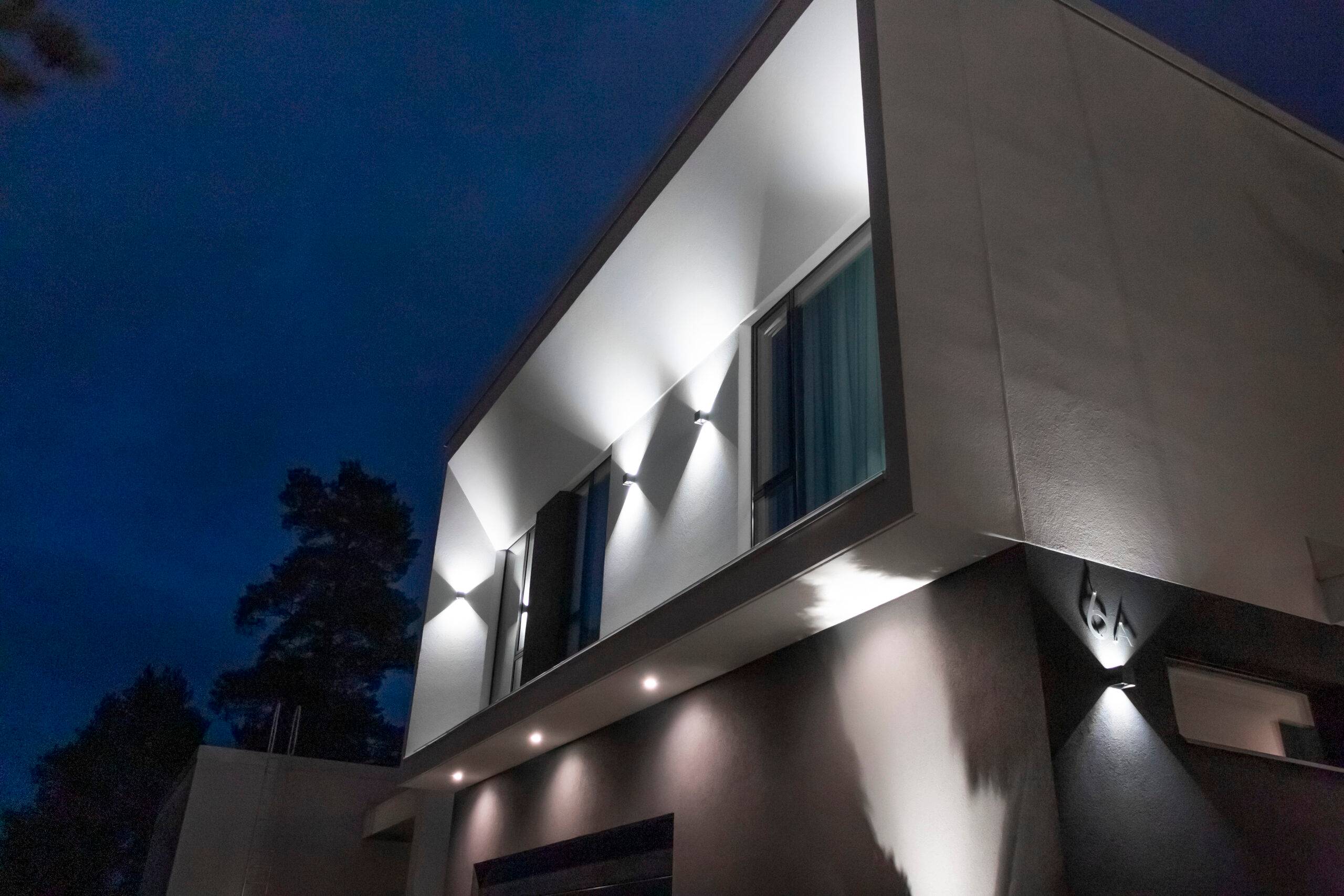 La iluminación led del patio se crea con apliques de pared y focos led que apuntan hacia abajo. Además, un aplique ilumina el número de la casa. 