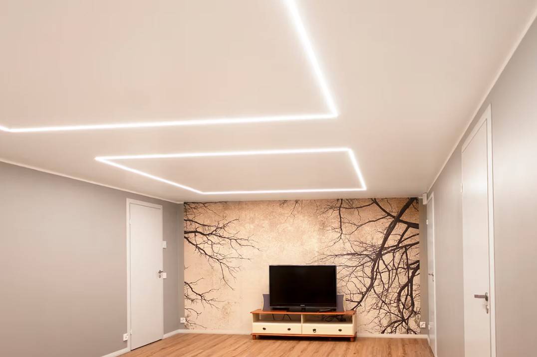 Un salón minimalista en una casa familiar de Kaitamäki, Espoo, donde las lámparas LED de techo de LedStore.fi crean un elegante esquema de iluminación. El salón cuenta con una mesa de TV y un llamativo mural, acentuados por iluminación LED de alta calidad.