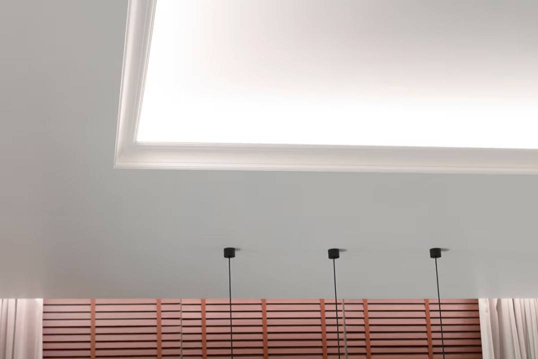 Un paquete de iluminación funcional para el salón. La tira de LED de la repisa de la lámpara de techo ilumina hacia el techo y hacia abajo, hacia las cortinas.