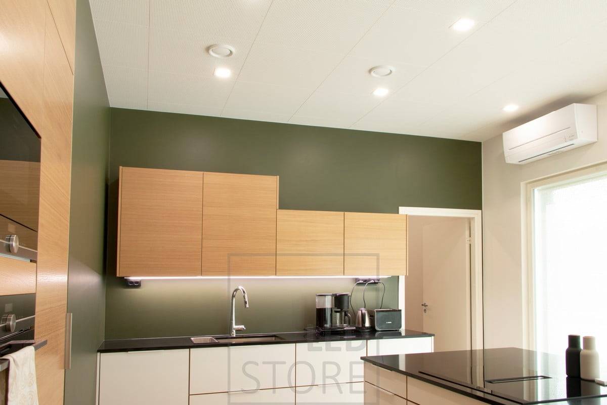 Iluminación de techo plana en la cocina con paneles LED cuadrados y una tira de luz LED en la parte inferior de los armarios superiores como iluminación plana. Ledstore.fi 