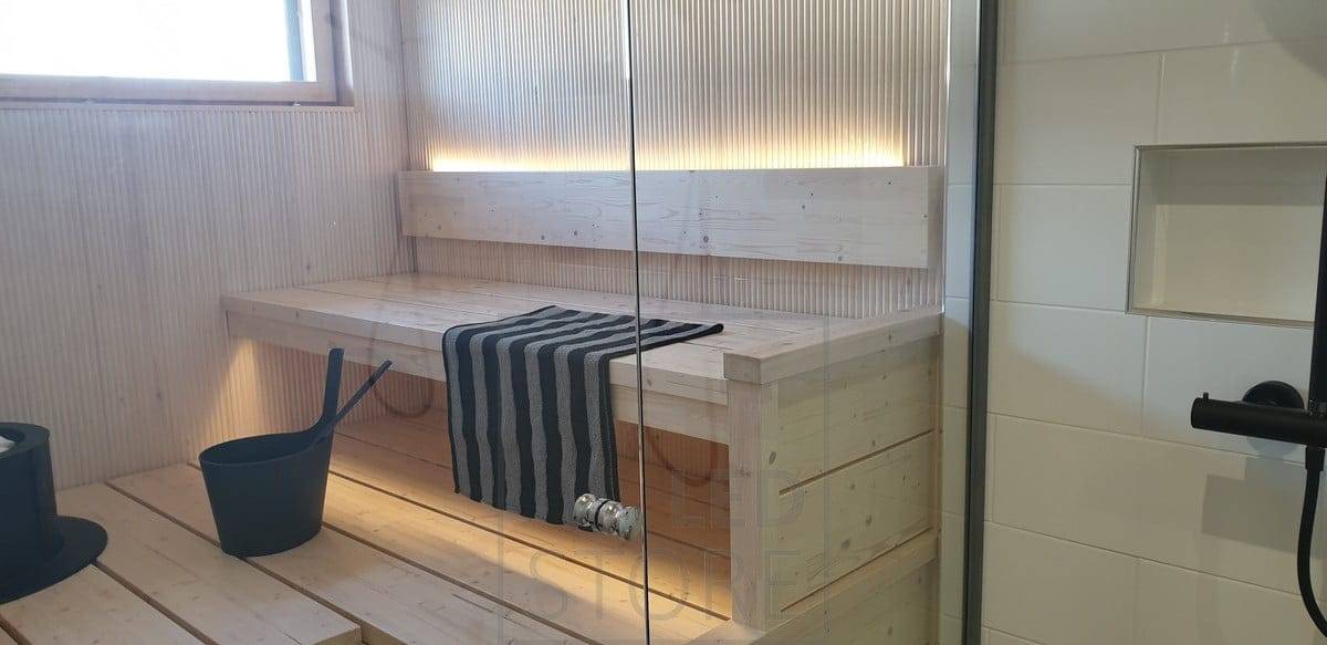 El respaldo de la sauna tiene una tira de LED que proporciona luz atmosférica hacia arriba y hacia abajo por debajo del techo. Ledstore.fi