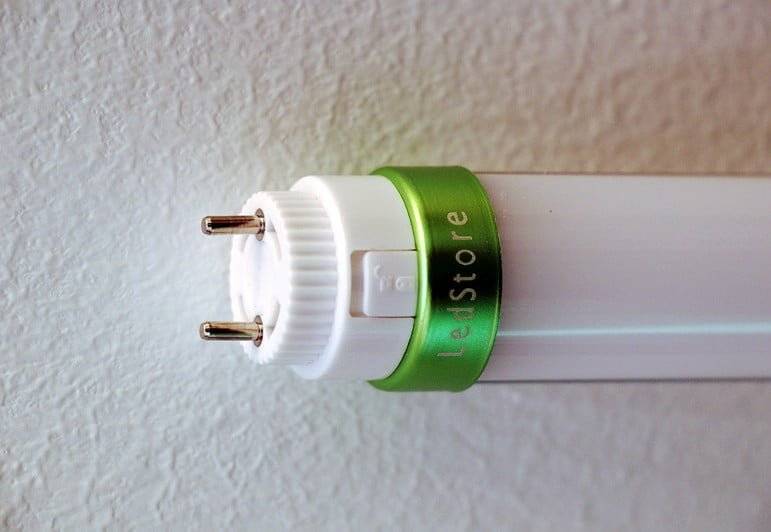 Primer plano del tubo de luz LED desde un extremo, mostrando dos patillas metálicas y el logotipo de LedStore.fi.