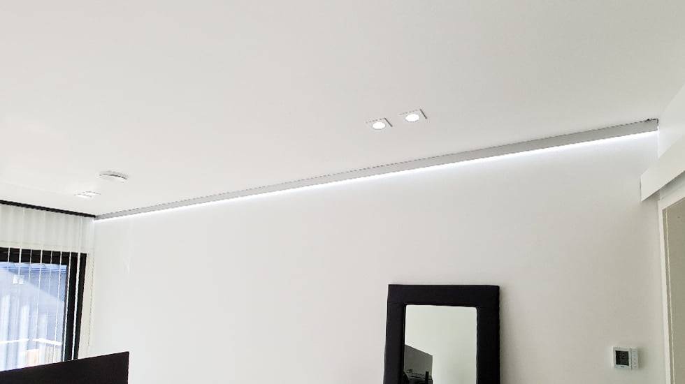 Luz indirecta en el límite techo-pared con luz blanca fría.