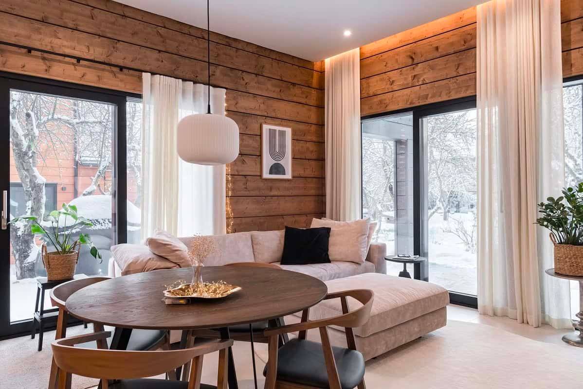 Un salón moderno y cálido con downlights LED de LedStore.fi que resaltan las superficies de madera y la arquitectura del espacio.