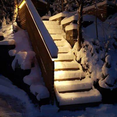 Las escaleras exteriores cubiertas de nieve reflejan la luz de la balaustrada.