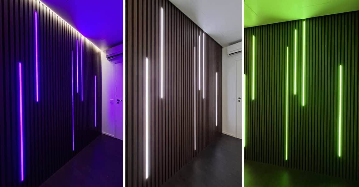 Una pared oscura elegantemente panelada con LED de LedStore.fi que brillan en azul, blanco y verde.