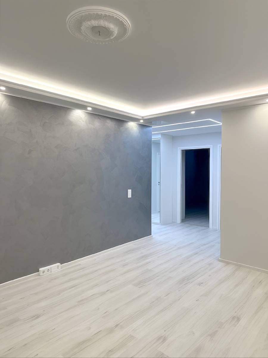 Estructura de techo con caída desde los bordes de la sala, con iluminación indirecta de tiras de LED y focos descendentes.