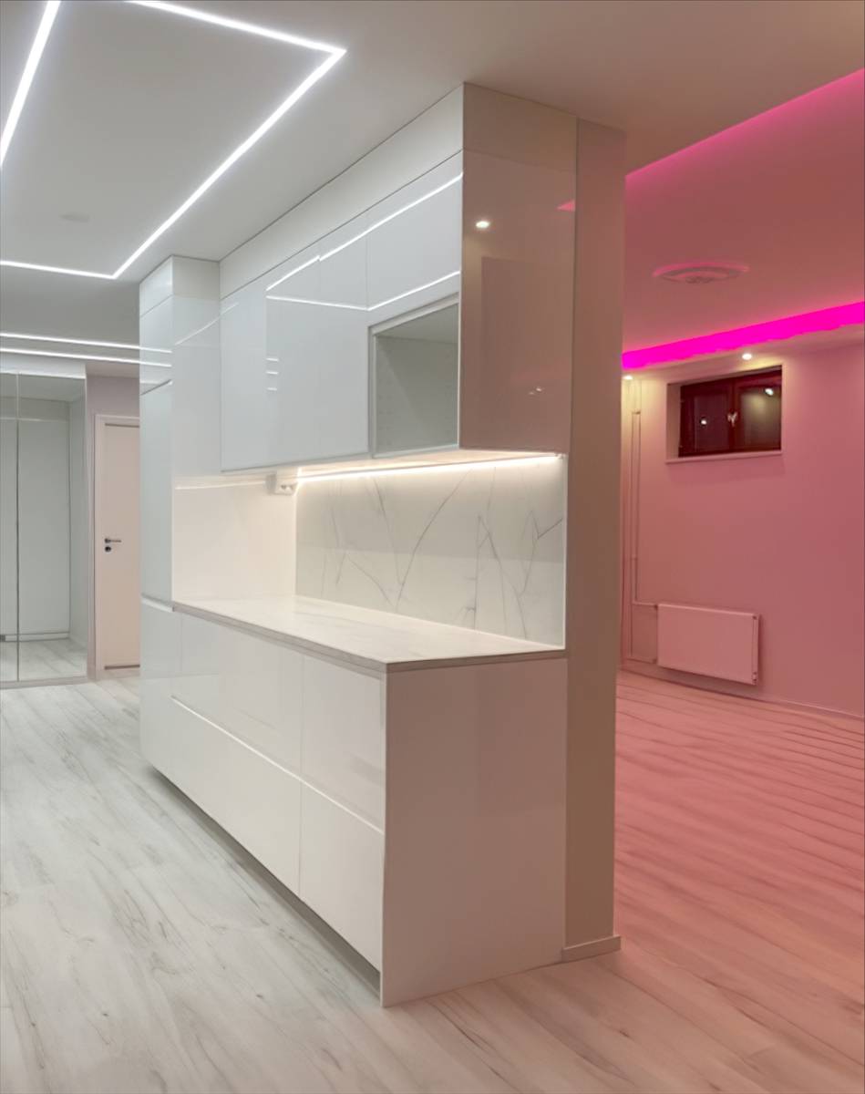 Línea de luz cuadrada en el techo de la cocina y luz led rosa en el salón.